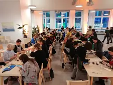 Das Bild zeigt eine Veranstaltung im Forum Küche, bei der viele Menschen gemeinsam an Tischen Lebensmittel vorbereiten.