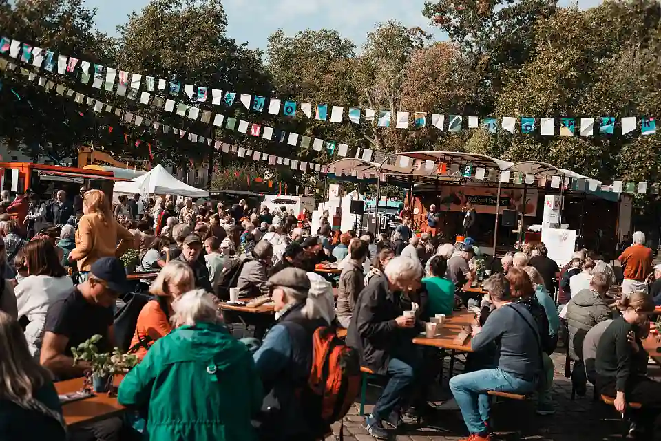 Besucher:innen des Biomarktfests sitzen gemeinsam an Bierzeltgarnituren und genie&szlig;en die entspannte Atmosph&auml;re.