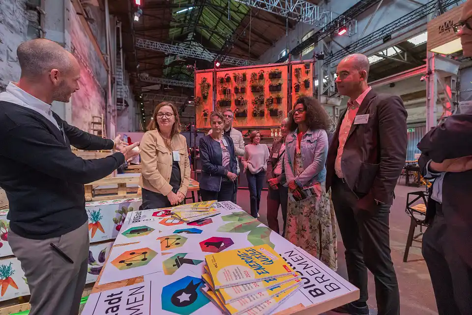 Mehrere Personen stehen vor einem Tisch, auf dem Brosch&uuml;ren liegen. Jan Kolhlm&uuml;ller von der BioStadt Bremen stellt das Projekt "Forum K&uuml;che" vor. 