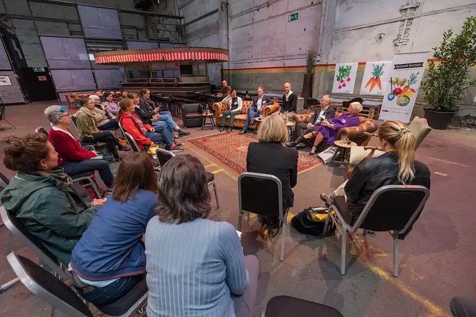 Mehrere Personen sitzen in einem Stuhlkreis und h&ouml;ren einer Person zu.