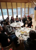 Fortbildung Küchenfachkräfte: Das Bild zeigt eine Gruppe von Küchenfachkräfen, die um zwei Tische herum sitzen und ihre selbstgemachten Snacks probieren.. 
&tilde; Bildnachweis: Hans-Wendt-Stiftung