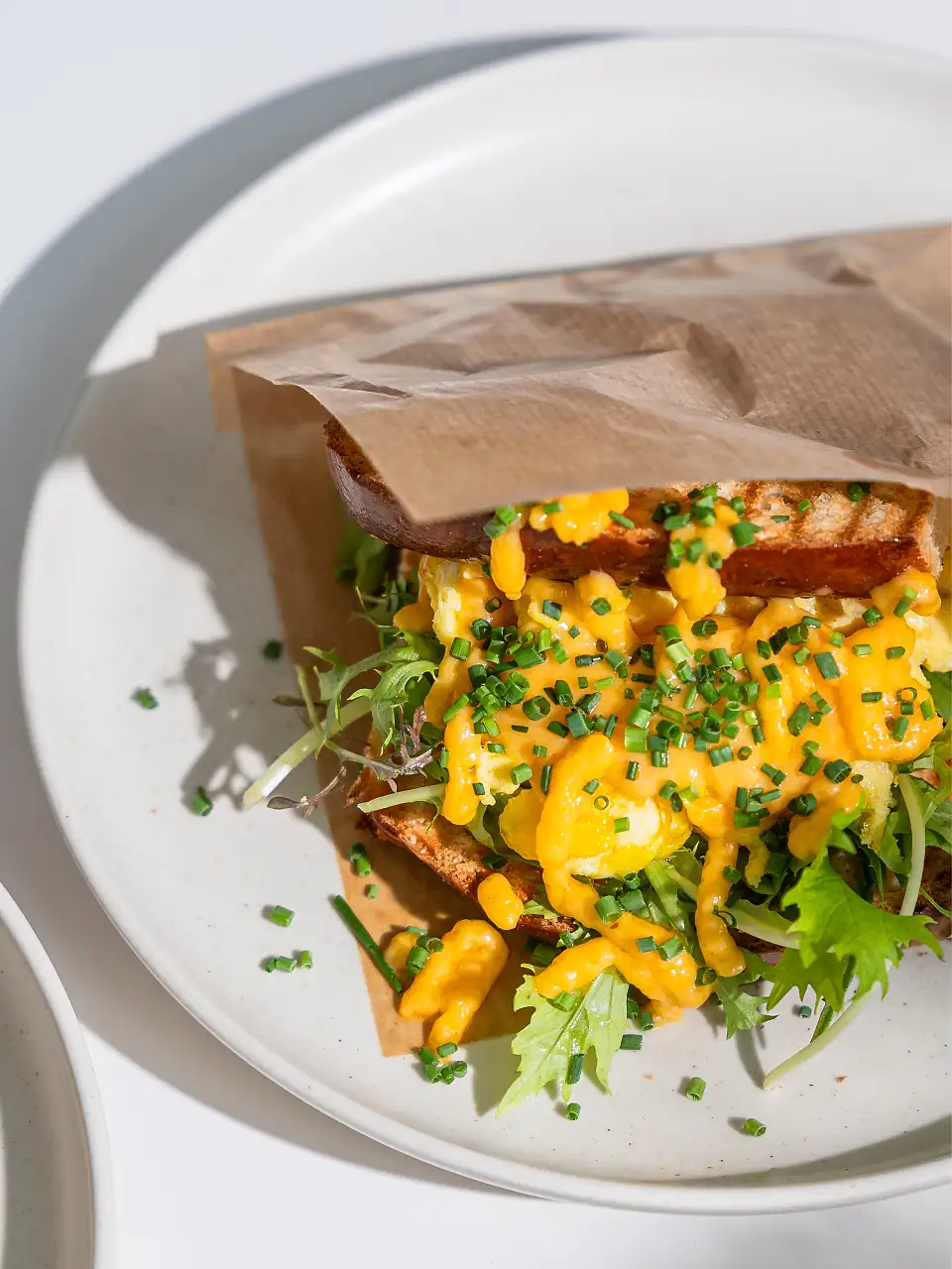 Das Bild zeigt ein kunstvoll angerichtetes Sandwich auf einem wei&szlig;en Teller.