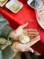 Kinderhände halten rohen Teig für ein Brötchen; im Hintergrund Teigschüssel und Sesam. 
&tilde; Bildnachweis: Verein Sozialökologie e.V.