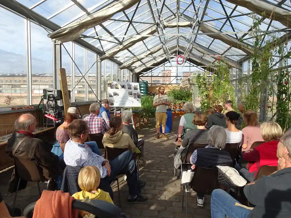 Watertuun: Lucas Lansing erkl&auml;rt das Prinzip einer Aquaponikanlage im Watertuun-Gew&auml;chshaus.  Dort werden die Pflanzen mit den Ausscheidungen der Fische ged&uuml;ngt. Die Fische befinden sich in gro&szlig;en Tr&ouml;gen im Keller. Fischanlage und Pflanzen sind durch Leitungen verbunden.